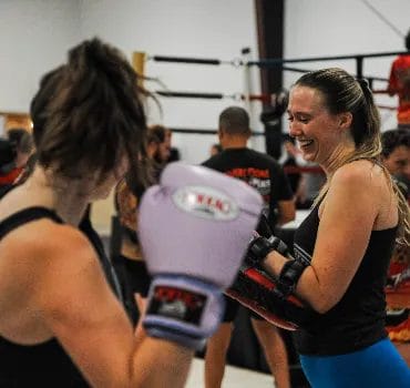 Two women practicing muay thai pad work and striking drills during class at Muaythai Iyarin